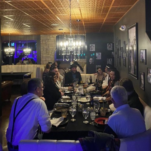 A group of people dining together at a restaurant, seated around a table with elegant decor and dim lighting.