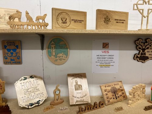 A display of wooden crafts and signs, including a lighthouse, holiday decor, and a payment notice.