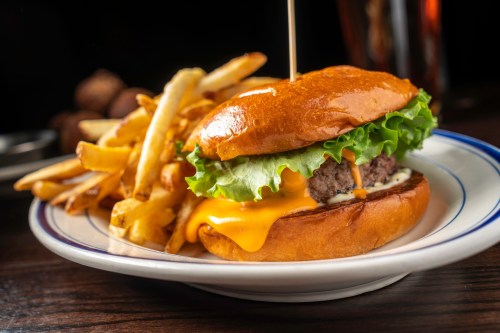 A juicy cheeseburger with lettuce on a toasted bun, served with a side of crispy French fries.