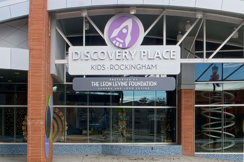 Exterior of Discovery Place Kids-Rockingham, featuring a colorful sign and modern architecture.
