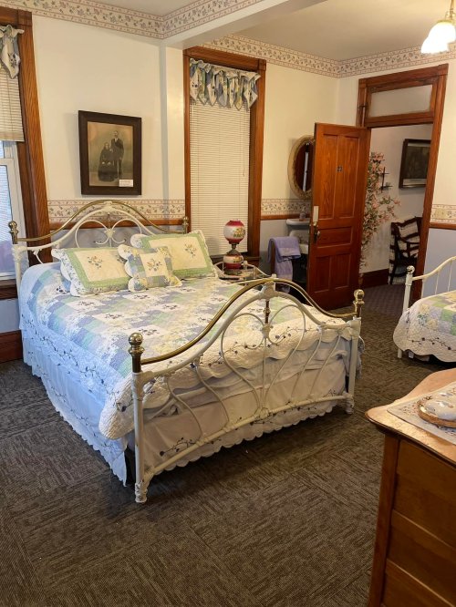 Cozy bedroom featuring a vintage bed, floral bedding, wooden furniture, and warm, inviting decor.