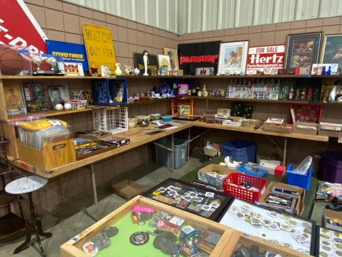 A cluttered display of various collectibles and antiques on tables in a market setting.