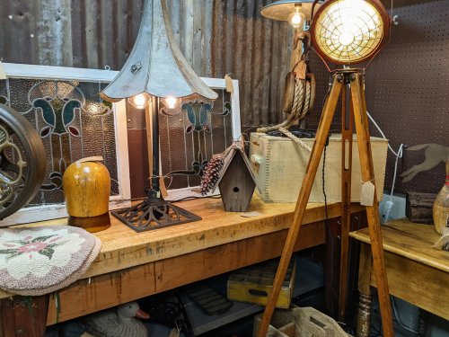 A cozy display of vintage items, including lamps, a birdhouse, and decorative objects on a wooden table.