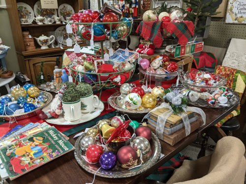 A festive display of colorful Christmas ornaments, decorations, and a holiday book on a table with a cozy atmosphere.
