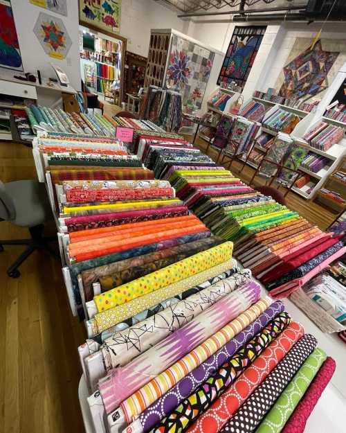 A colorful display of fabric rolls in a craft store, showcasing various patterns and textures.