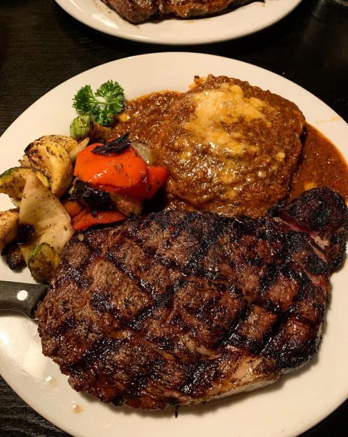 A plate featuring a grilled steak, savory sauce, mashed potatoes, and assorted grilled vegetables.