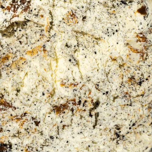 Close-up of a textured surface with creamy white and dark speckled patterns, resembling a dessert or creamy spread.