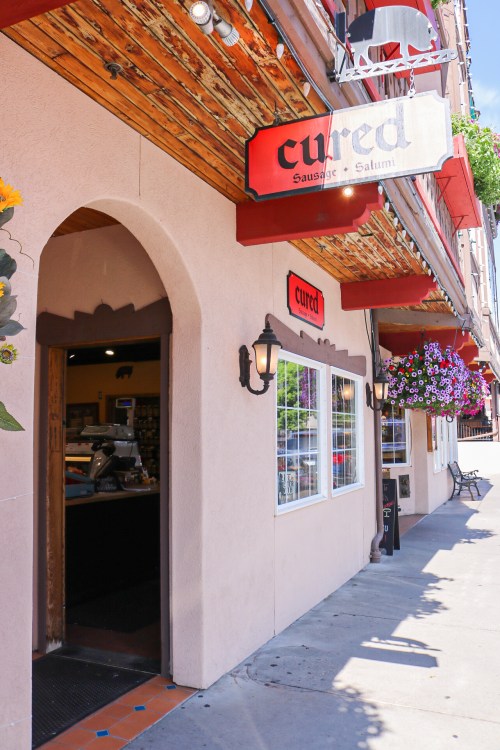 Exterior of a shop named "curd," featuring a welcoming entrance and colorful flower baskets.