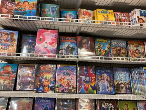 A shelf filled with various animated movie DVDs, including titles like "Frozen," "Trolls," and "Peter Rabbit."