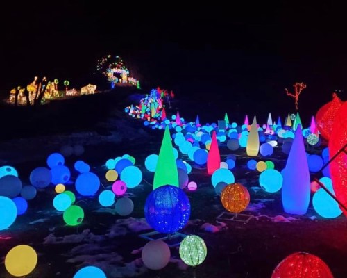 A colorful display of glowing orbs and conical lights in a festive outdoor setting at night.