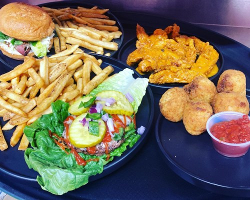 A tray of food featuring a burger, fries, buffalo wings, and fried balls with a side of salsa.