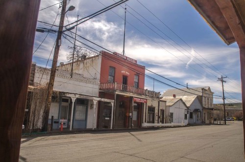 Historic buildings line a quiet street, featuring the prominent red facade of the Washington Hotel under a blue sky.