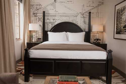 Cozy bedroom featuring a large bed, architectural wall art, two lamps, and a stylish rug.