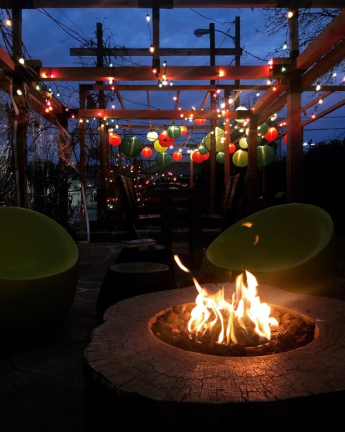 Cozy outdoor space with a fire pit, colorful lanterns, and string lights, creating a warm evening atmosphere.