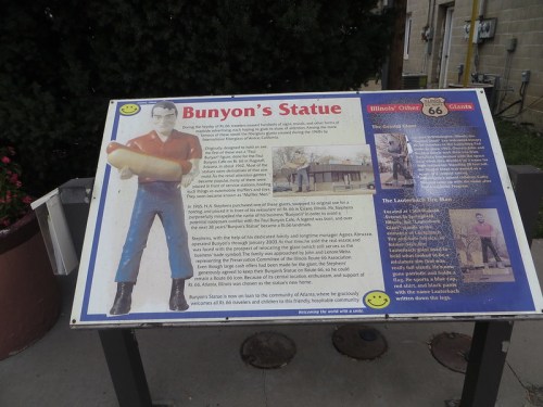 Sign about Bunyon's Statue, featuring a figure holding a large hot dog, with historical information and Route 66 references.