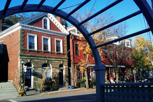 A charming street scene featuring historic brick buildings and autumn foliage under a clear blue sky.