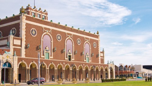 Historic building with ornate architecture, featuring arched windows and decorative elements, set against a clear blue sky.
