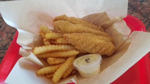 A basket of golden fried fish fillets and crinkle-cut fries, served with a small container of dipping sauce.