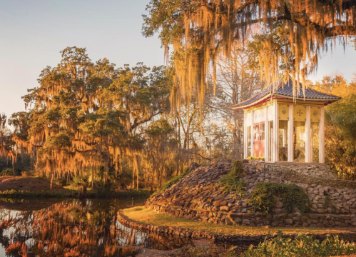 A serene gazebo by a pond, surrounded by trees draped in Spanish moss, illuminated by warm sunset light.