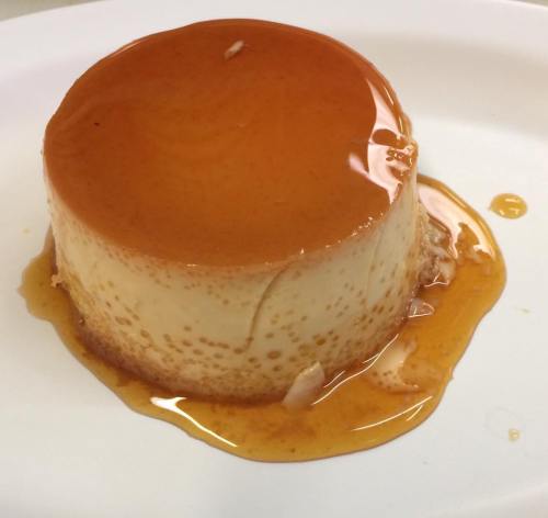 A smooth, round flan topped with a glossy caramel sauce, sitting on a white plate.