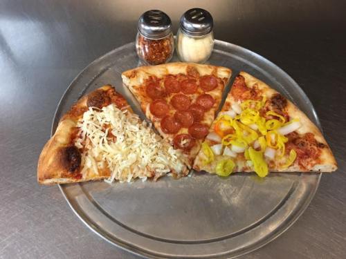A pizza plate with three slices: one with cheese, one with pepperoni, and one topped with onions and peppers, alongside seasonings.