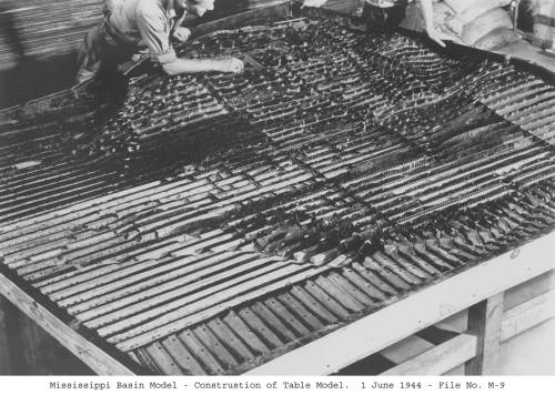 A worker constructs a detailed model of the Mississippi Basin, showcasing intricate landforms and waterways.