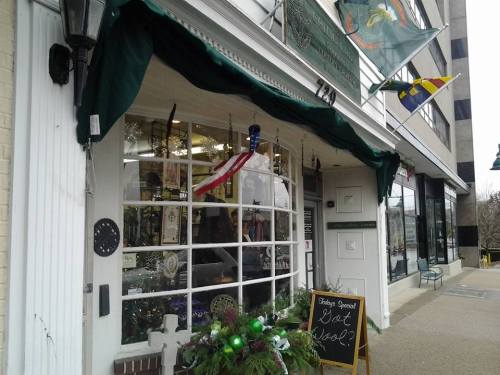 A cozy storefront with a green awning, displaying festive decorations and a sign that reads "Got Wool?"