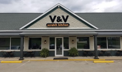 Exterior of V&V Scratch Kitchen, featuring a welcoming entrance and outdoor seating under a cloudy sky.