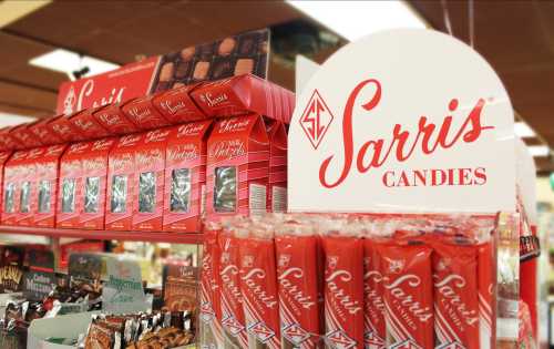 Display of Sarris Candies products, featuring red packaging and a prominent sign for the brand.