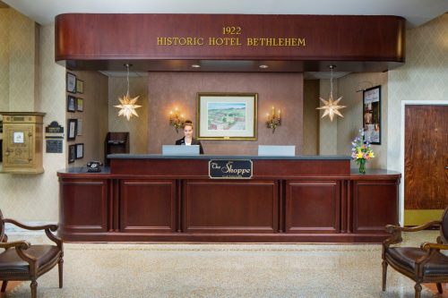 Reception area of the Historic Hotel Bethlehem, featuring a wooden desk, a staff member, and decorative lighting.