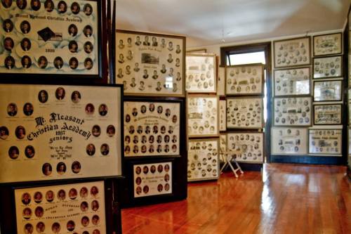 A room filled with framed portraits and plaques from Mt. Messina Christian Academy, showcasing senior class photos.