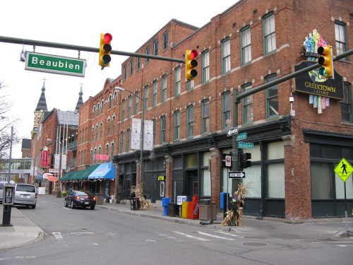 Street view of brick buildings, traffic lights, and signs in Greektown, with a casino and shops visible.