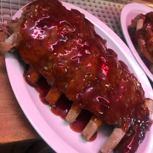 A plate of ribs covered in a thick, glossy barbecue sauce, with several meaty bones visible.