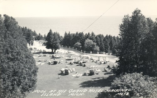 A vintage photo of a pool area at the Grand Hotel on Mackinac Island, surrounded by trees and overlooking the water.