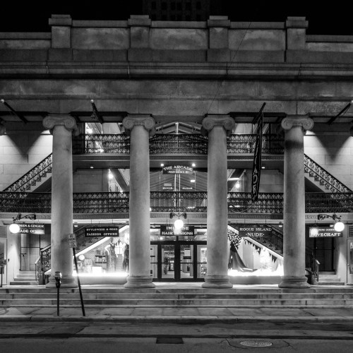 A historic building at night, featuring grand columns, intricate railings, and illuminated signage.
