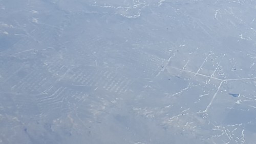 A close-up view of a smooth, icy surface with faint patterns and textures visible beneath the ice.