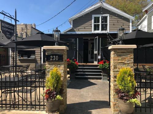 Exterior view of Bowdies Chophouse, featuring a welcoming entrance, outdoor seating, and vibrant flower planters.