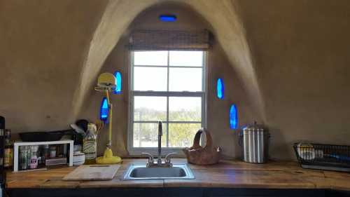 A cozy kitchen with a wooden countertop, sink, and blue circular windows, featuring a warm, earthy design.