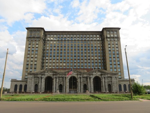 Historic building with a grand facade, featuring large windows and ornate architectural details, set against a cloudy sky.