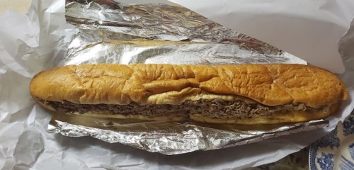 A long sandwich in foil, filled with shredded meat and served in a toasted hoagie roll.