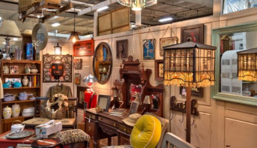 A cozy antique shop filled with vintage furniture, lamps, and decor items on display.