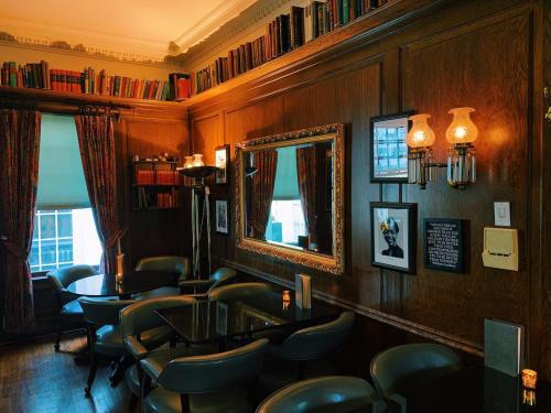 Cozy interior of a room with wooden walls, bookshelves, elegant lighting, and dark furniture.