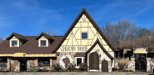 A charming, rustic building with a steeply pitched roof, featuring stone accents and a sign that reads "Brat Haus."