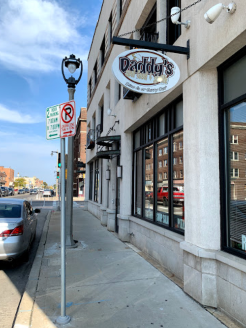 Exterior view of Daddy's restaurant with a sign, street parking signs, and a clear blue sky in the background.