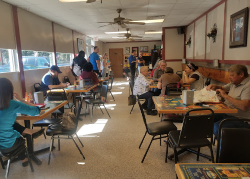 A busy restaurant interior with patrons seated at tables, chatting and enjoying meals in a casual setting.