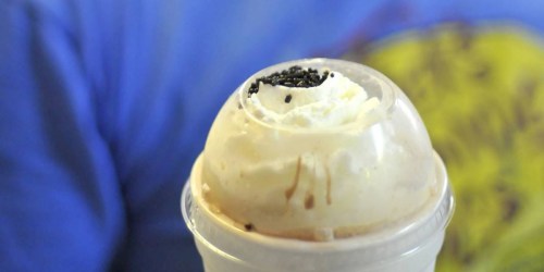 A close-up of a creamy dessert topped with whipped cream and chocolate sprinkles in a clear cup.