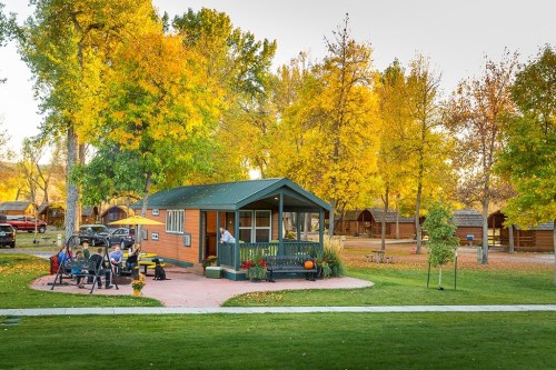 A cozy cabin surrounded by vibrant autumn trees, with a patio and seating area in a serene outdoor setting.