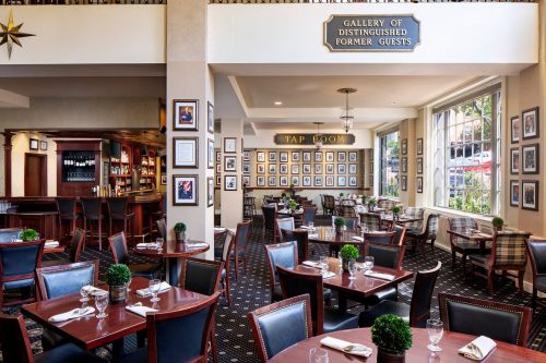 Elegant restaurant interior featuring tables, a bar, and a gallery of framed photos on the walls.