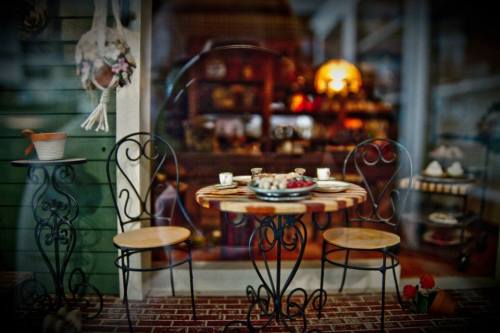 A cozy miniature dining setup with a round table, two chairs, and a spread of food, set against a charming background.