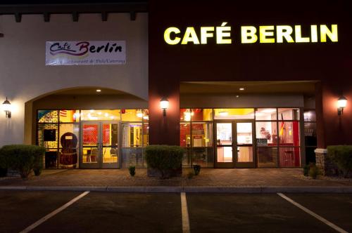 Exterior view of Café Berlin, featuring a brightly lit sign and welcoming entrance, with parking in front.